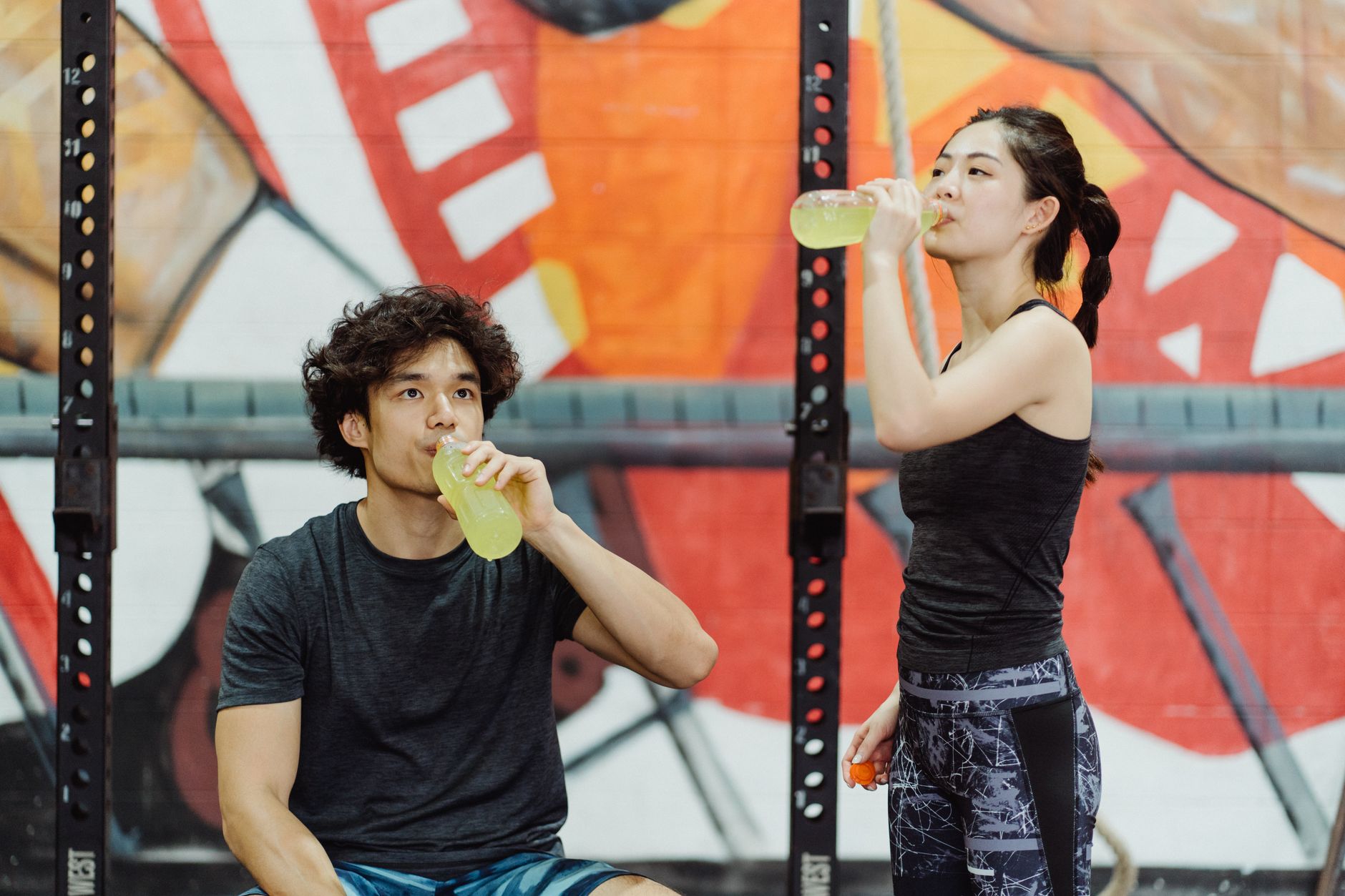 Couple in activewear drinking electrolyte beverages at an indoor gym