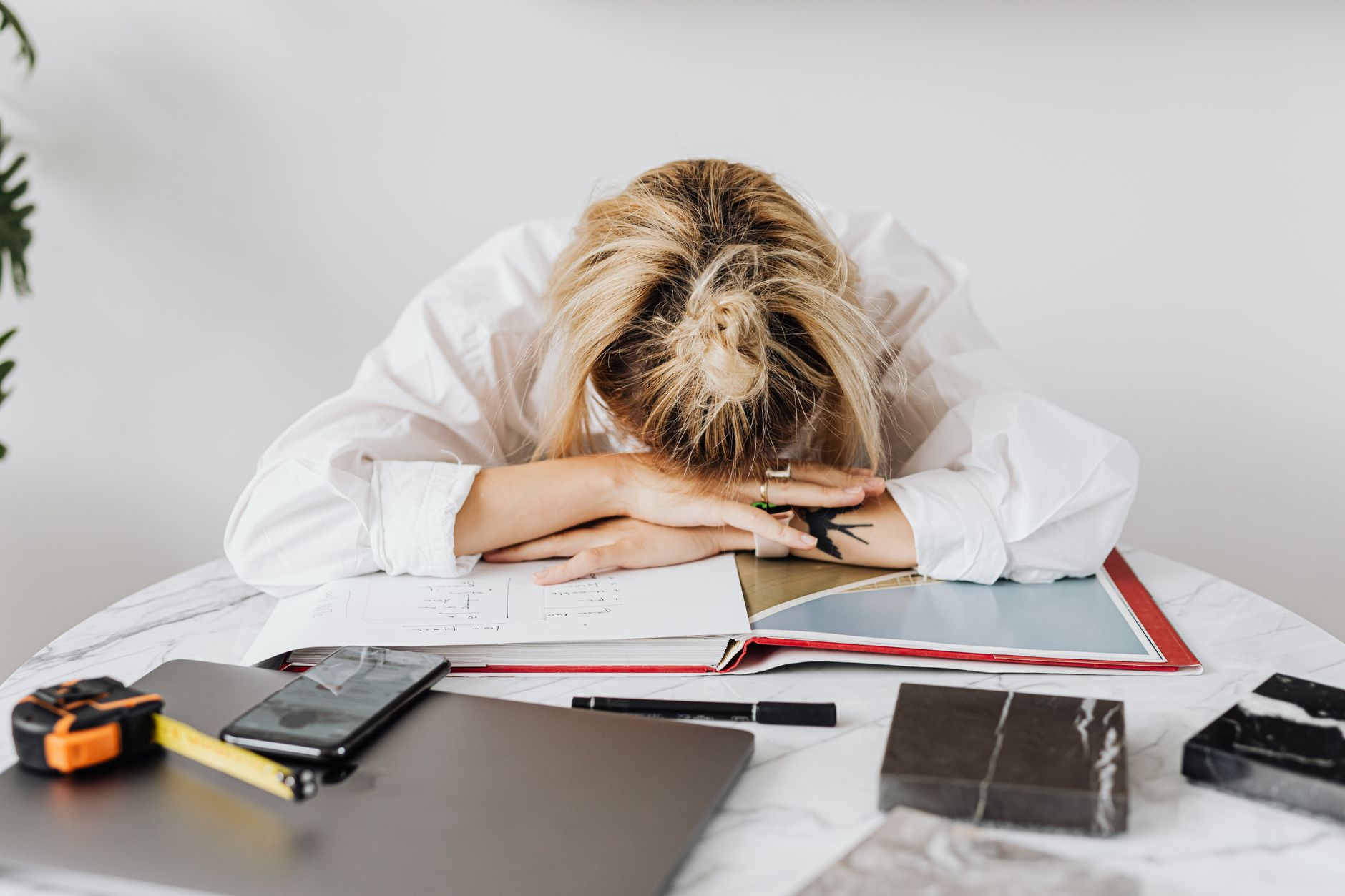 Tired woman resting her head on a desk filled with work materials